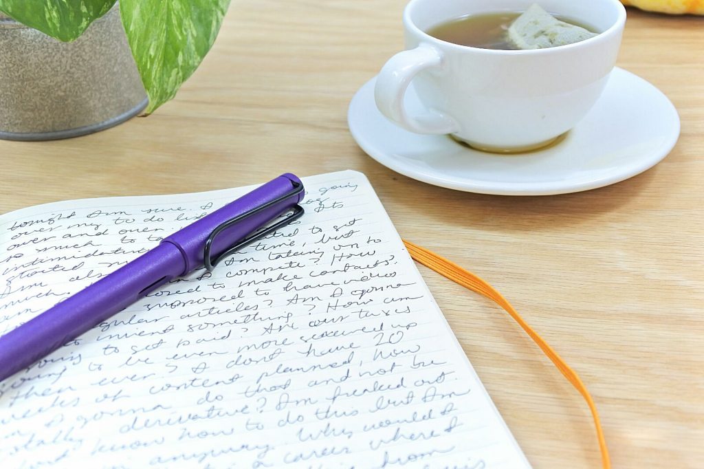 writing in a rhodiarama with a purple lamy safari while drinking tea